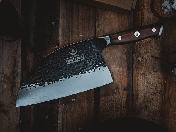 Hand-forged meat cleaver with a tall broad blade resting on a wooden butcher block