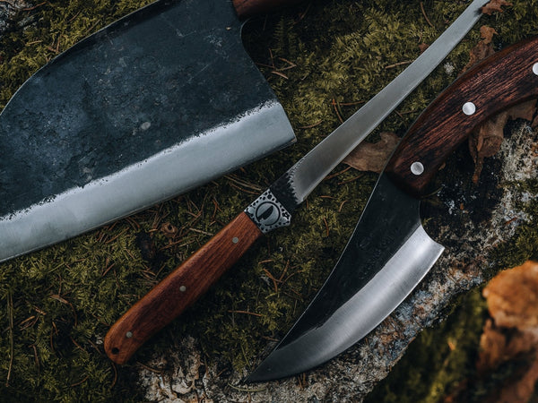 Budget kitchen knife set laid out on a wooden board, three hand-forged blades