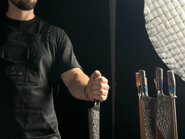 Hand-forged Cooking Guild chef knife showing the ground bevel and fitted wooden handle