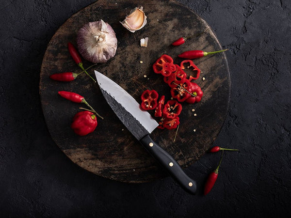 Hand-forged paring knife trimming produce on a wooden board