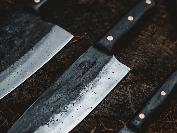 Carbon steel kitchen knife blade with a dark grey patina developed through use