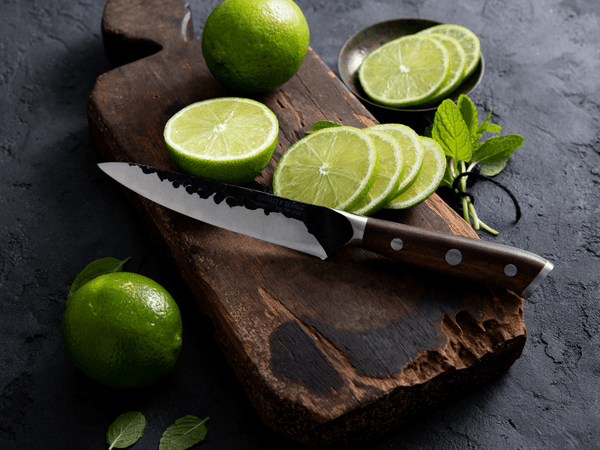 Hand-forged petty knife and paring knife side by side on a wooden board