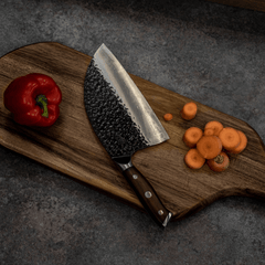 Serbian cleaver resting on a cutting board beside prepared vegetables